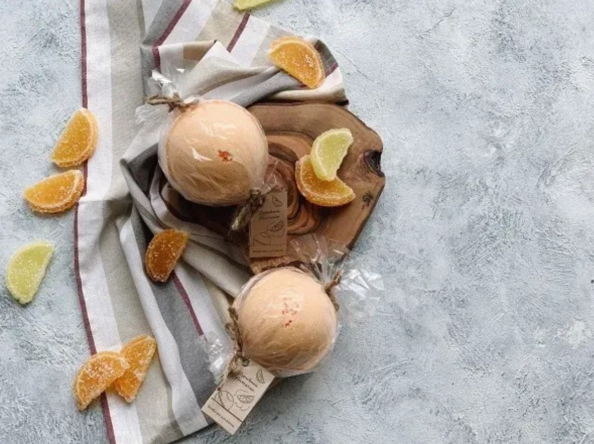 Handmade citrus bath bombs wrapped and arranged on a striped linen cloth
